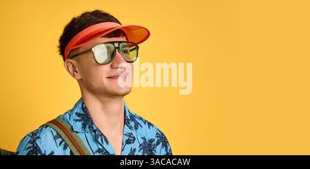 Banner. Nahaufnahme eines fröhlichen jungen Mannes mit orangefarbenem Visier und Sonnenbrille, der zufrieden und träumerisch aussieht. Stockfoto