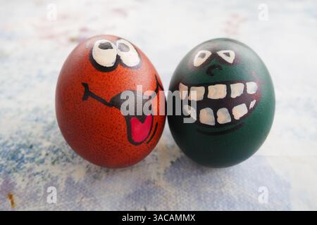 Ostereier, grün und braun gefärbt mit bemalten, lachenden Gesichtern. Lustige Grimassen mit Augen, Zunge und großen weißen Zähnen. Unheimliches Gesicht für Halloween. Emoticon Stockfoto