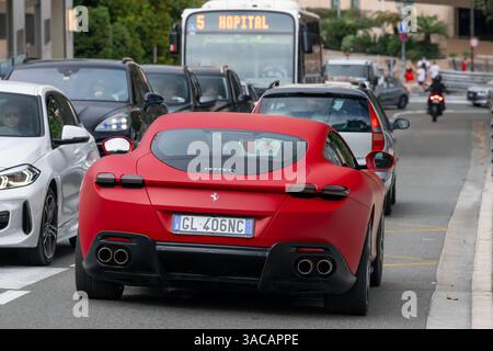 Monte Carlo, Monaco - Blick auf einen mattroten Ferrari Roma, der auf einer Straße im Stau fährt. Stockfoto