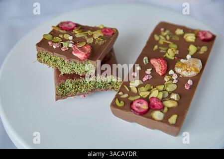 Dubai Schokolade. Reichhaltige Schokoladenkunst, ein Hauch süßer Köstlichkeiten, verziert mit hellen Himbeeren und lebendigen Pistazien, die mit pu verziert werden Stockfoto