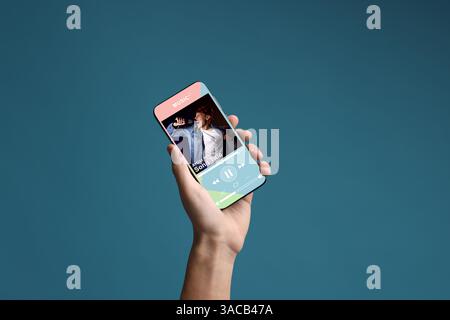 Mann zeigt Handy mit geöffneter Musik-Player-App auf blauem Hintergrund, Nahaufnahme Stockfoto