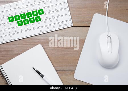 Online-Test. Computertastatur mit Wörtern, Maus und Schreibwaren auf Holztisch, Draufsicht Stockfoto