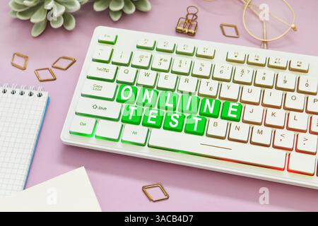 Online-Test. Computertastatur mit Wörtern und Schreibwaren auf rosa Tisch Stockfoto