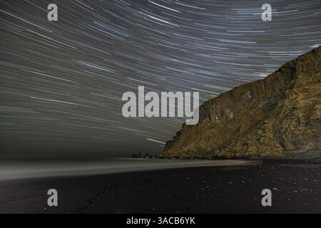 Island, Vik. Myrdal. Sternenpfade über dem schwarzen Sandstrand von Reynisfjara bei Nacht Stockfoto