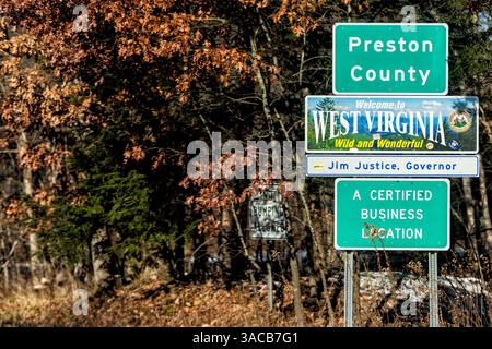 Aurora, USA - 20. November 2022: Preston County, West Virginia Road im Herbst mit Begrüßungsschild an der Staatsgrenze und roten Blättern auf Bäumen Stockfoto