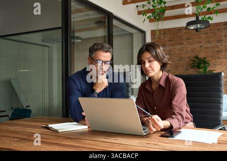 Zwei beschäftigte Geschäftsleute und Männer, die am Laptop arbeiten. Stockfoto