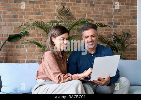 Lächelnder, reifer Geschäftsmann und Geschäftsfrau, der sich mit dem Notebook unterhält. Stockfoto