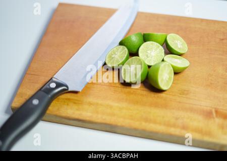 Geschnittene Limetten auf einem Schneidebrett mit Messer Stockfoto