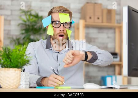 Geschäftsmann überfordert mit gelben Erinnerungsnotizen Stockfoto