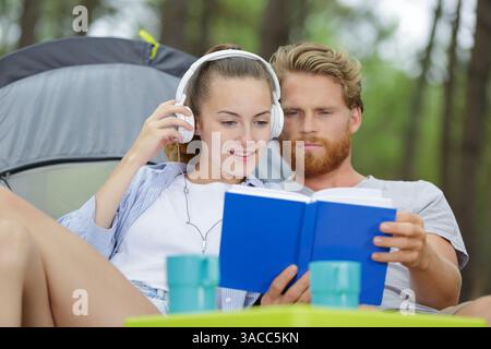 Mann liest Buch Freundin hört Musik in der Natur Stockfoto