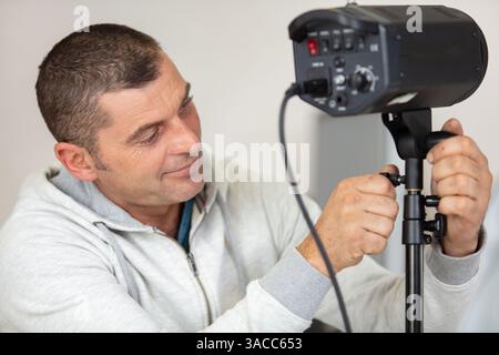 Der Mann passt die Beleuchtung im Fotostudio an Stockfoto