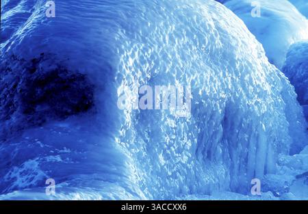 Aus nächster Nähe sehen Sie Steine, Klippen oder Felsen, die von Eis bedeckt sind. Winterabend am Meer, kalte und farbenfrohe Muster. Stockfoto