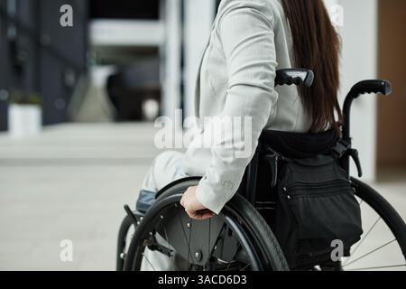 Abgeschnittenes Porträt einer jungen Geschäftsfrau im Rollstuhl beim Betreten des Bürogebäudes, Kopierraum Stockfoto
