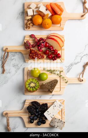 Lebendige vegane Käseplatten Flat Lay – farbenfroher Aufstrich auf Pflanzenbasis mit Obst, Gemüse, Nüssen, Brot und Blumen Stockfoto