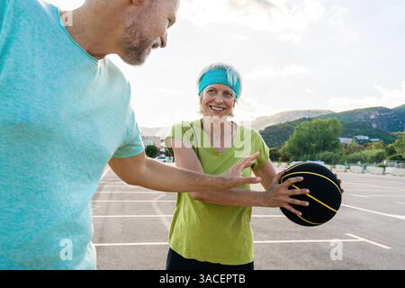 Wunderschönes glückliches Seniorenpaar, das Basketball spielt und Spaß hat - reifes verheiratetes Paar, das verliebt ist, sich im Freien zu verbinden und gemeinsam Sport zu treiben, Konzepte ab Stockfoto