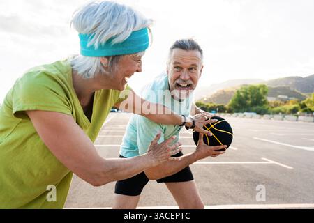 Wunderschönes glückliches Seniorenpaar, das Basketball spielt und Spaß hat - reifes verheiratetes Paar, das verliebt ist, sich im Freien zu verbinden und gemeinsam Sport zu treiben, Konzepte ab Stockfoto