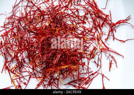 Leuchtende rote Safran-Pistil-Fäden stapeln sich isoliert auf weißem Marmorstein Hintergrund, hell und luftig mit Sonnenlicht Stockfoto