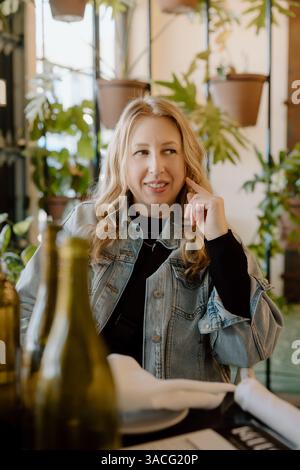 Frau in Jeansjacke lächelt am Restauranttisch Stockfoto