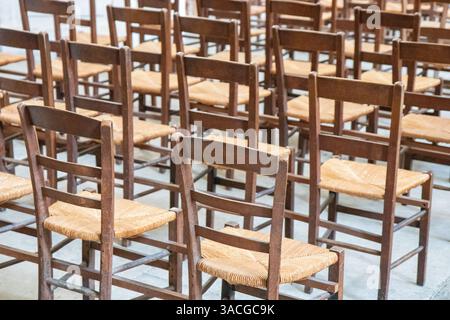Reihen von leeren alten Holzstühlen oder Stühlen in der Kirche, im Theater oder im Musikkonzert, abstraktes Muster. Stockfoto