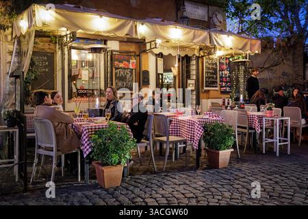 Rom, Italien - 31. März 2025: Abends in Trastevere, einem typischen Trattoria-Restaurant, das von Touristen in der Stadt besucht wird, mit Tischen und Stockfoto