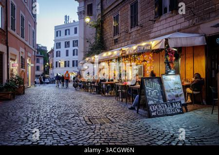 Rom, Italien - 31. März 2025: Abends in Trastevere, einem typischen Trattoria-Restaurant, das von Touristen in der Stadt besucht wird, mit Tischen und Stockfoto