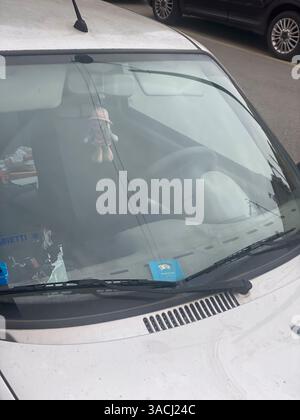 Crema, Italien - 2. März 2025 Windschutzscheibe eines geparkten silbernen Fiat 600 mit Parkscheibe, Puppe hängt am Rückspiegel und einem teilweise zerrissenen Highwa Stockfoto