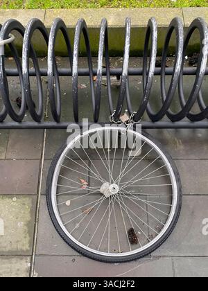 Crema, Italien - 2. März 2025 das Fahrrad, das sich an einem spiralförmigen Fahrradträger stützt und mit Kette und Vorhängeschloss gesichert ist, erinnert an Themen wie Diebstahl und Vandalismus Stockfoto