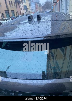 Crema, Italien - 2. März 2025 Regentropfen bedecken das Dach und die Heckscheibe eines geparkten grauen Range Rover Evoque an einem regnerischen Tag und spiegeln die Umgebung wider Stockfoto