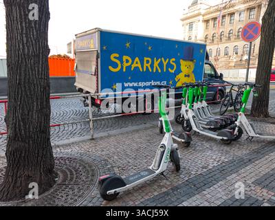 Prag, Tschechische Republik - 25. März 2025: Elektroroller können gemietet werden, die auf dem Bürgersteig in der Nähe eines Sparks-Lieferwagens auf dem wenzelsplatz geparkt werden Stockfoto