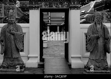 Zwischen den stillen Wächtern wandert ein Kind durch das Tempelgelände des Wat Pho Stockfoto