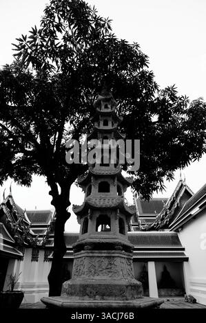 Steinpagode eingerahmt von Tempeldächern und grünen Schatten im Wat Pho Stockfoto