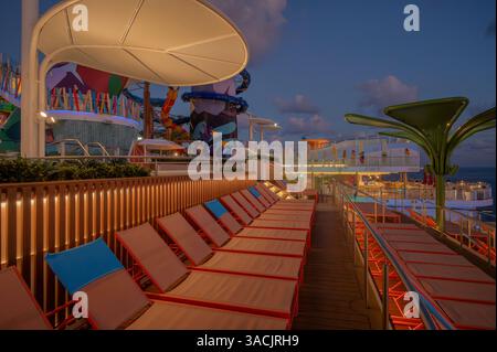 Sonnenaufgang über Liegestühlen auf einem Kreuzfahrtschiff in der Karibik auf den Bahamas Stockfoto