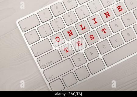 Online-Test. Computertastatur mit Tasten, die Wörter auf Holztisch machen, Draufsicht Stockfoto