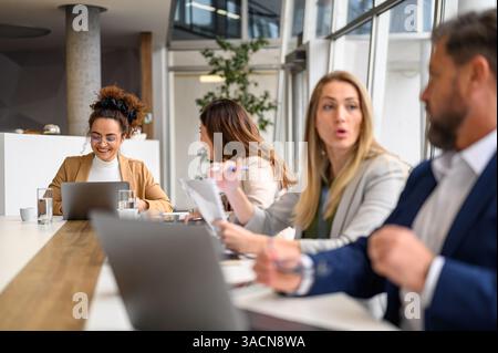 Gruppe von professionellen Unternehmern, die Strategien miteinander diskutieren, während sie zusammen im Sitzungssaal sitzen Stockfoto