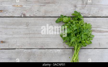 Ein Haufen frischer, glatter Petersilie auf hellem hölzernem Hintergrund, Stockfoto