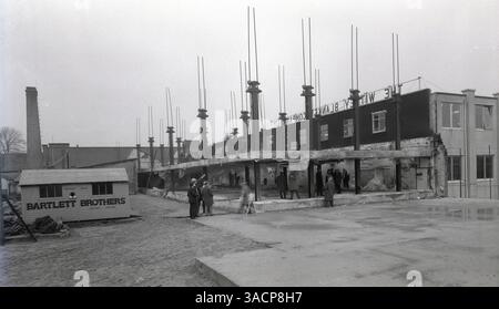 1950er Jahre, historische Bauarbeiten an den Buttercross Works der Whitney Blanket Company Ltd, Whitney, Oxford, England, Großbritannien. Bauunternehmer Bartlett Brothers (Whitney) Limited, wie auf der Bauhütte zu sehen. Whitney Decets wurde 1885 als Decken-Veredelungs- und Reinigungsunternehmen gegründet und entwickelte sich dann in einem Geschäft, das Decken über den Versandhandel verkauft. Die kleine Stadt Witney in Oxfordshire wurde berühmt für ihre Decken, die in die ganze Welt exportiert wurden. Stockfoto