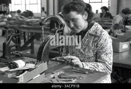 1930er Jahre, historisch, eine junge Frau mit Blumenmuster, die insgesamt in einer Fabrikwerkstatt arbeitete, die Lederuhrbänder herstellt, in South Wales, Großbritannien. Stockfoto