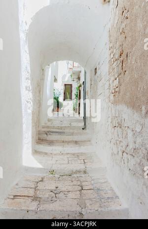 Enge, weiß getünchte Gasse mit Bogen und Treppen, die zu einem typischen Haus in Ostuni, Apulien, Italien führen Stockfoto
