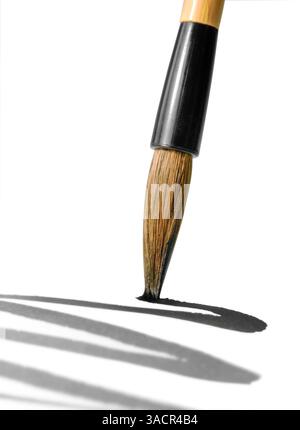 Detail eines chinesischen Pinsels beim Zeichnen einer lebendigen schwarzen Linie auf der weißen Rückseite Stockfoto
