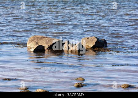 Große Felsen mit Steinen liegen im Wasser an der Ostseeküste Stockfoto