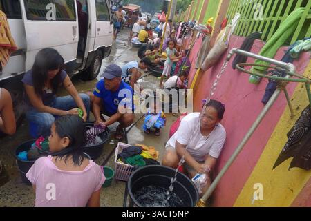 27. Dezember 2011 - Cagayan de Oro, Philippinen - Flutopfer waschen sich ihre Kleidung und erfrischen sich entlang der Straße in Cagayan de Oro City, Südphilippinen. Zwei Wochen nach der Sturzflut durch den Tropensturm Washi muss die Stadt das Wassersystem erst wieder herstellen, nachdem es durch die Sturzflut beschädigt wurde. 80 Prozent der Stadt leiden immer noch unter Wasserknappheit. (Bild: © Keith Bacongco/ZUMAPRESS.com) Stockfoto