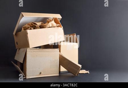 Papier- und Pappverschmutzungs- und Recyclingkonzept mit einem Stapel von Kartonschachteln auf schwarzem Boden isoliert auf schwarzem Hintergrund. Vorderansicht. Stockfoto