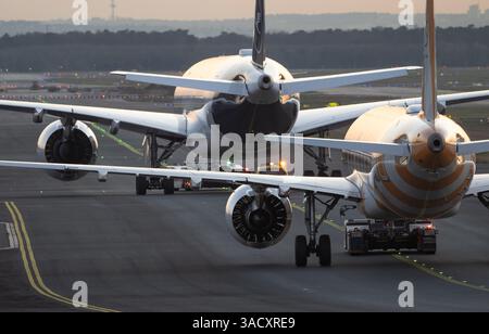04. April 2025, Hessen, Frankfurt/Main: Lufthansa und Condor Passagierflugzeuge werden in der letzten Abendbeleuchtung am Frankfurter Flughafen auf ihre Parkposition geschleppt. Foto: Boris Roessler/dpa Stockfoto