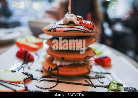 Golden Brown Pancakes mit Creme, Obst und Schokoladensirup Stockfoto