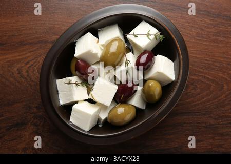 Marinierte Oliven mit Fetakäse und Rosmarin auf Holztisch, Blick von oben Stockfoto