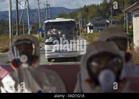 12. November 2011 - Tokio, Japan - Japanische Beamte mit Schutzanzügen und Masken fahren hinten in einem Bus, während ein zweiter Bus mit Beamten und japanischen Journalisten auf ihrem Weg durch die kontaminierte Sperrzone zum verkrüppelten Kernkraftwerk Fukushima Dai-ichi in Okuma, Japan, am Samstag, 12. November 2011, folgt. (Kreditbild: © David Guttenfelder-Pool/Jana Press/ZUMAPRESS.com) Stockfoto