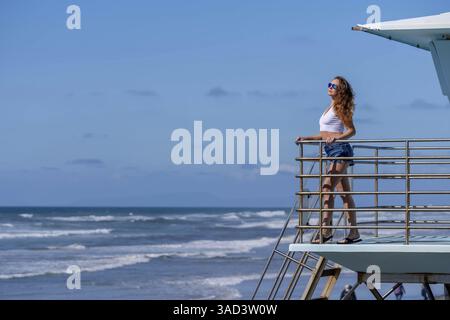 Atemberaubende Frau sonnt sich in der Nähe eines Piers, unter klarem blauem Himmel und genießt die Ruhe eines perfekten Tages am Meer, La Jolla, United Sta Stockfoto