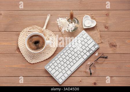 Moderne Tastatur, Korbmatte und Tasse Kaffee auf hölzernem Hintergrund Stockfoto