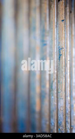 Eine kalte Makrostudie von vertikal ausgerichteten Metallstäben, die abgebrochene Farbe und subtile Patina durch geringe Schärfentiefe zeigt Stockfoto