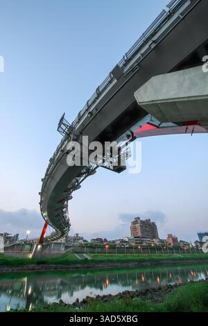 Wenn die Dämmerung verblasst, leuchtet Taipeis Regenbogenbrücke, deren Bögen sich auf den Keelung River spiegeln, ein friedlicher Zufluchtsort in der belebten Stadt. Stockfoto